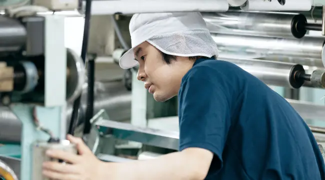 グラビア印刷機を操作しながら作業する社員の様子