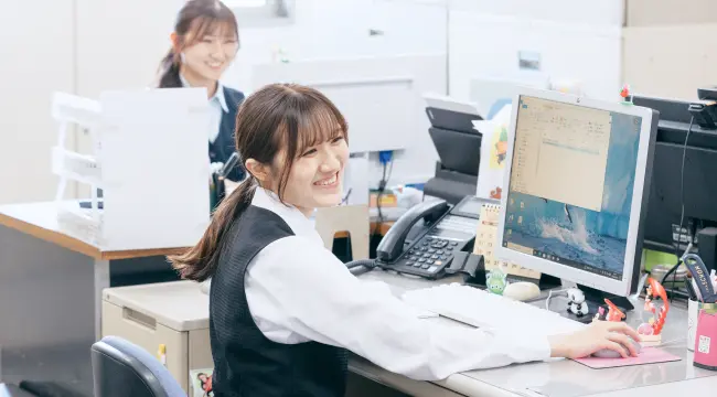 オフィスで笑顔で働く女性社員の様子